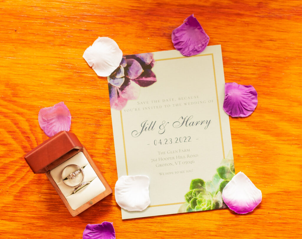 Jill and Harry's wedding details, wedding rings, flower petals, and ring box.