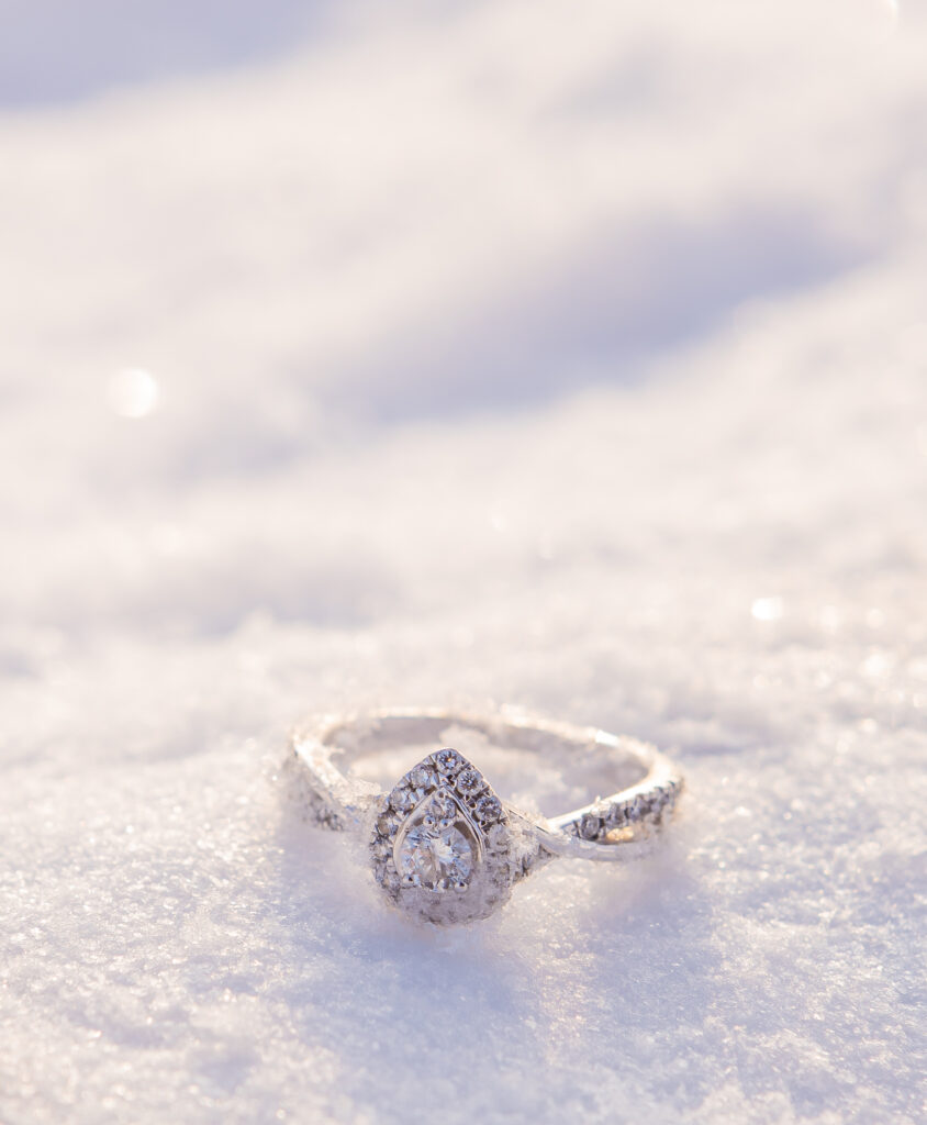 A sparkly engagement ring submerged in the New Hampshire snow. 