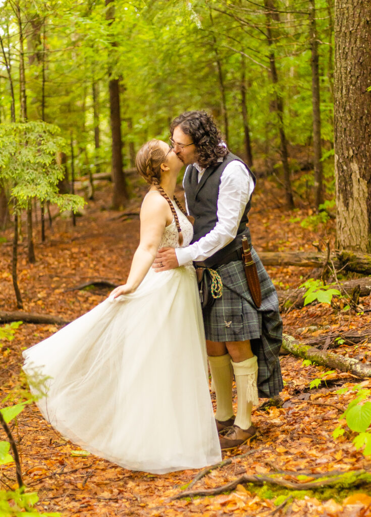 The bride fluffs her dress and leans in for a kiss in the White Mountain National Forest.
