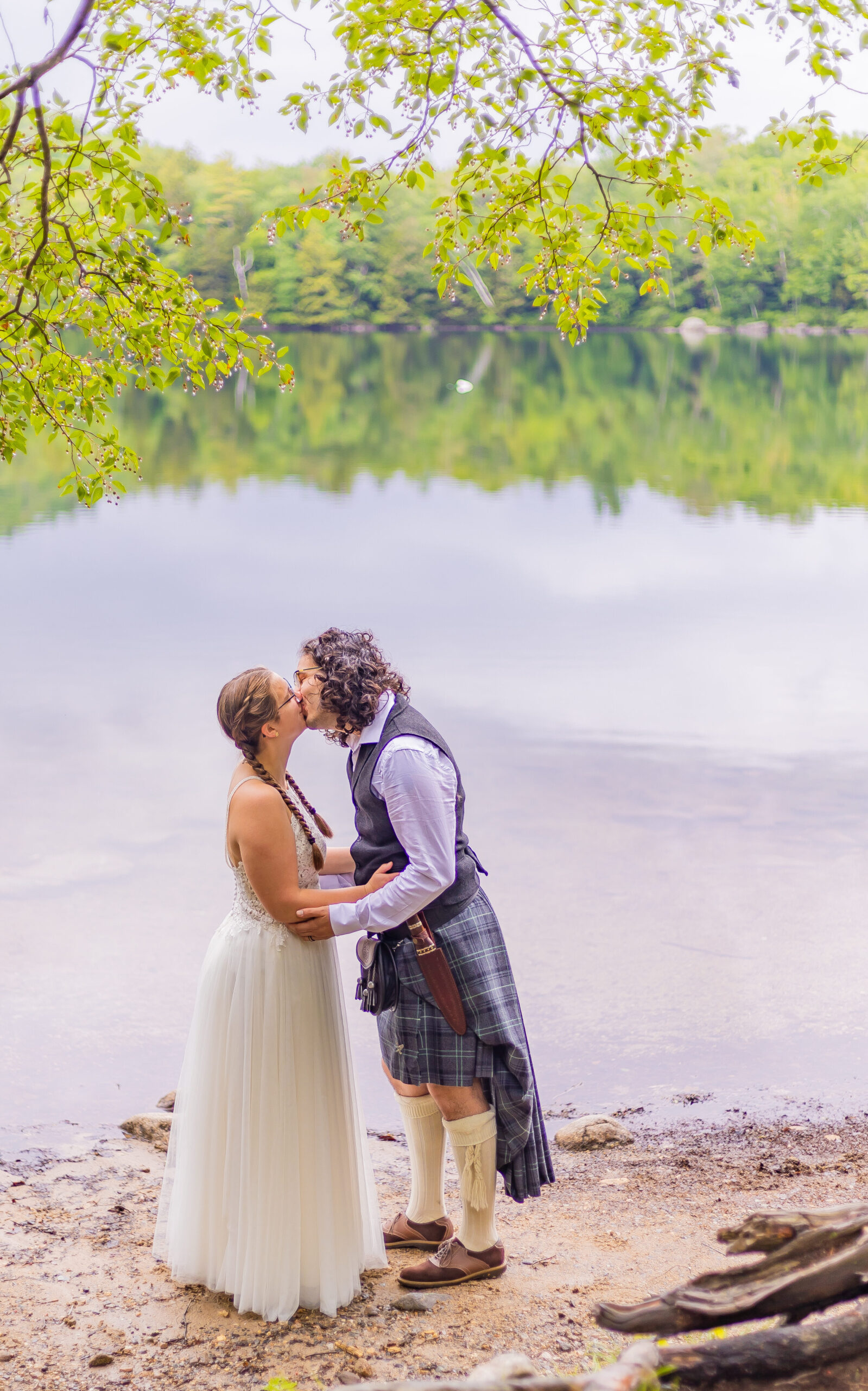The bride and groom share a kiss in front of Russell Pond in Franconia Notch.