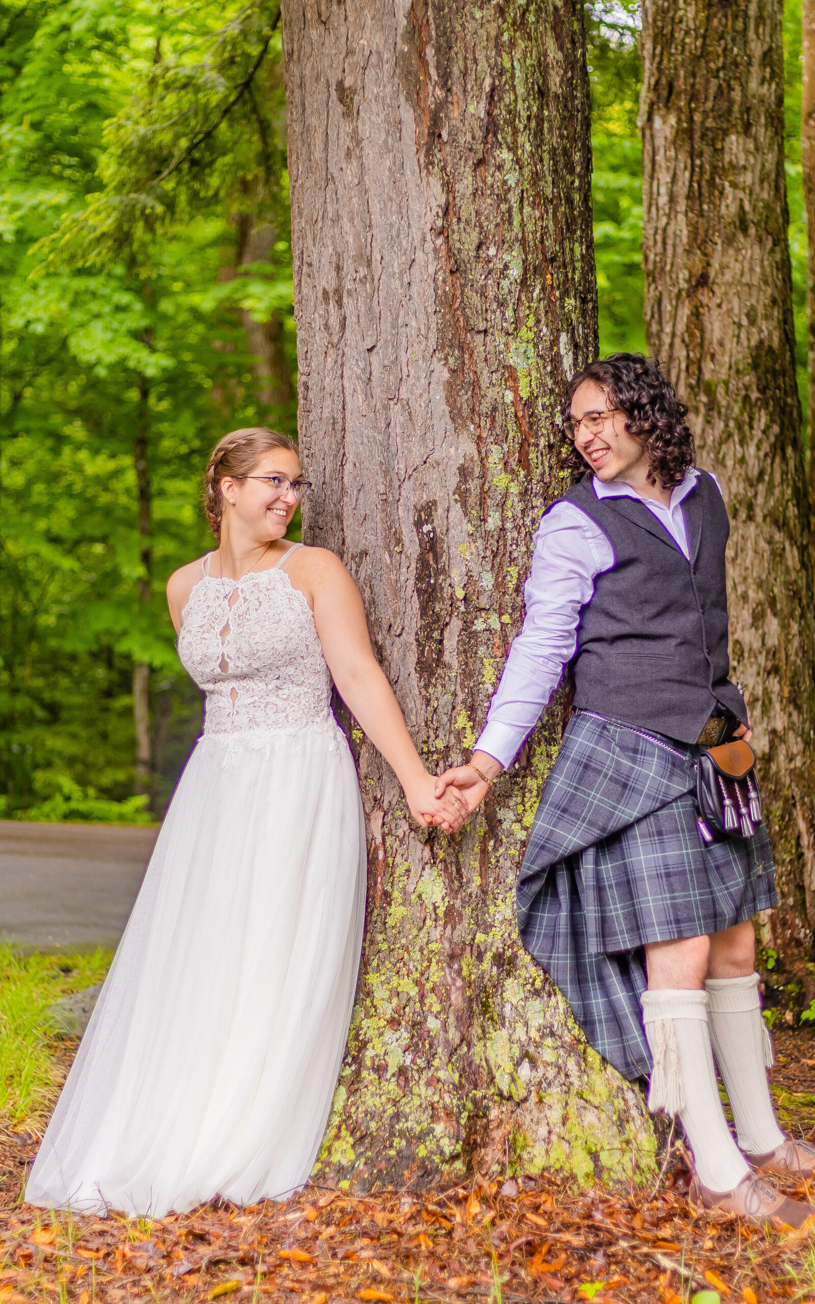 The bride and groom peer around a tree at one another at Russell Pond in Campton NH.