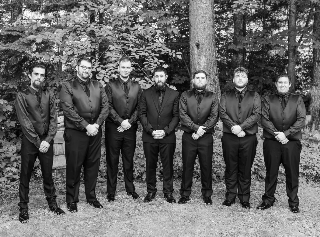 The groomsmen stand together with their arms crossed for a squad picture.