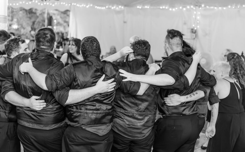 The groomsmen hold each other and sing during the wedding. 
