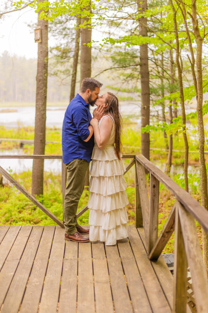 a couple stands on a porch together at a scenic photography spot in NH