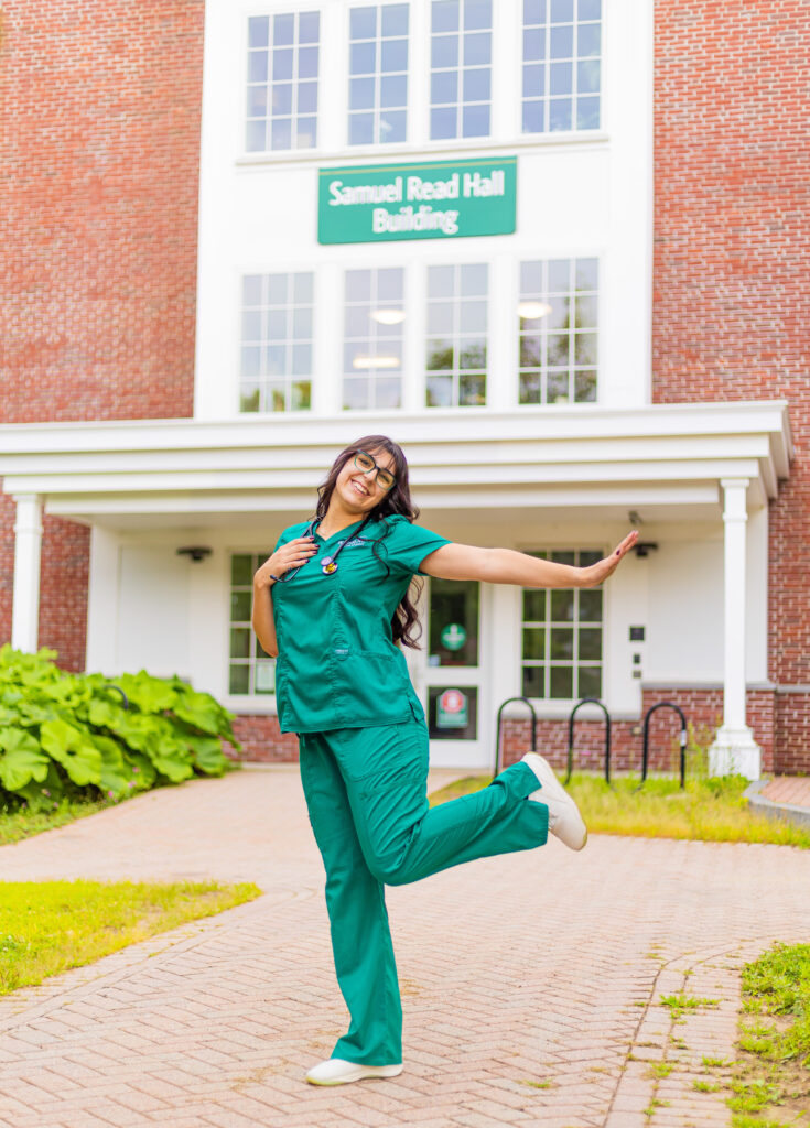 A senior at PSU poses in front of the nursing program building. 
