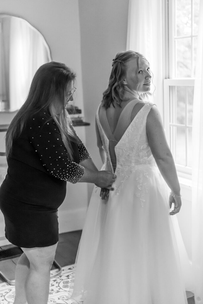 Mom helps the bride zip up her dress at a wedding venue in New Hampshire