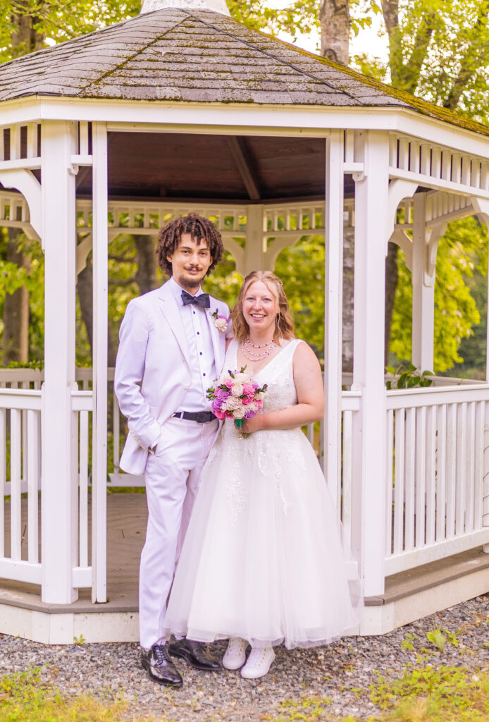 Bride and groom standing in front of a gazebo at their NH wedding venue.