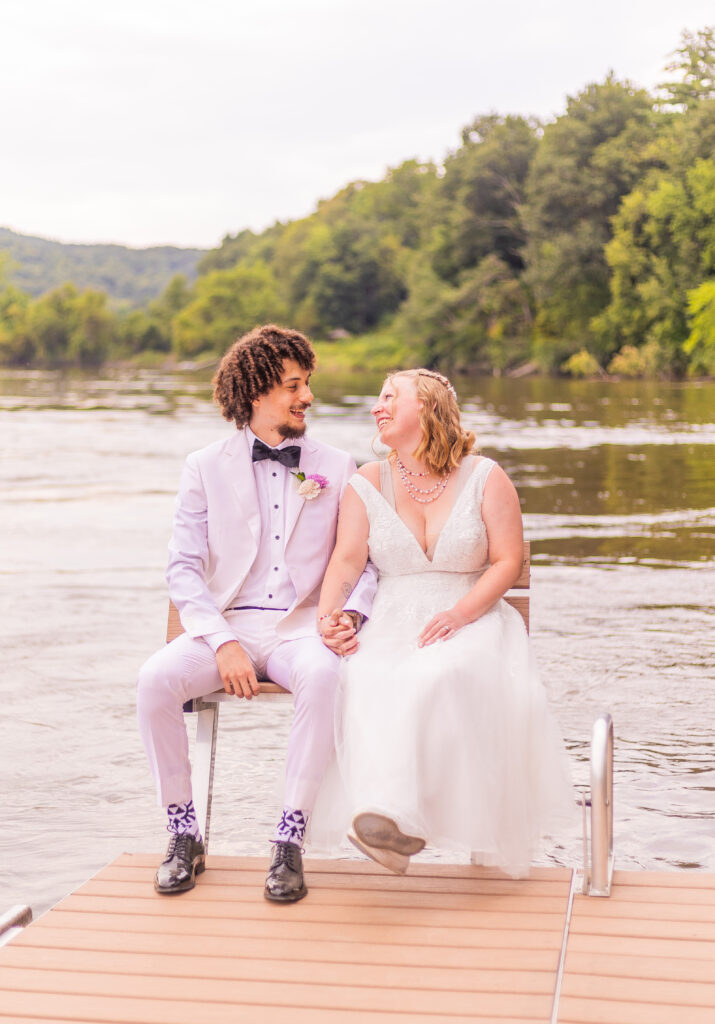 Bride and groom sit together on the dock at their wedding in Westmoreland, NH.