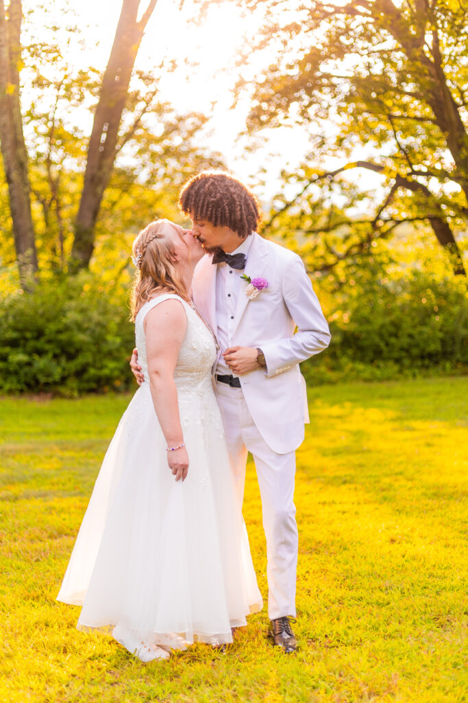 Bride and groom kiss during golden hour.