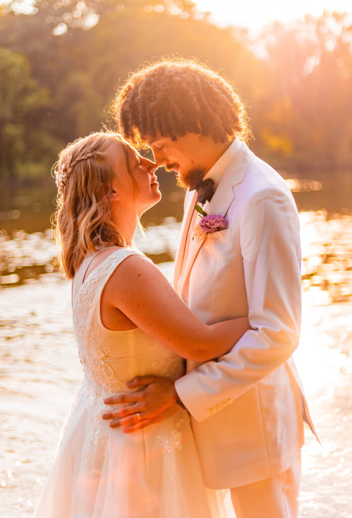Bride and groom touch noes uder the golden hour sun.