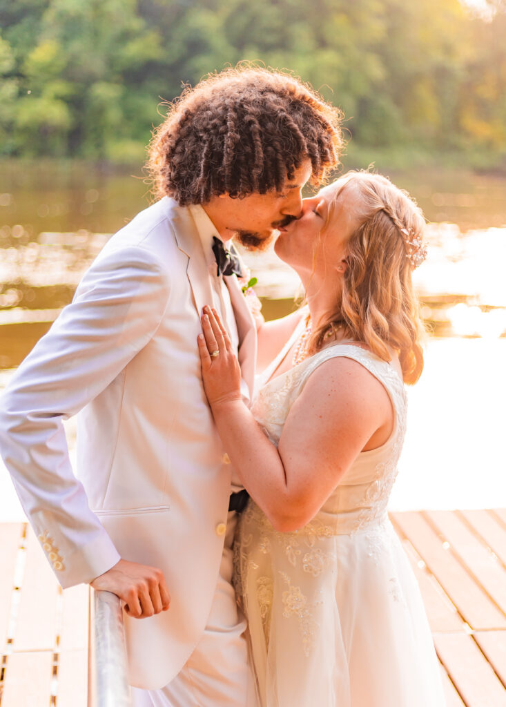 Bride and groom share a kiss on a dock.