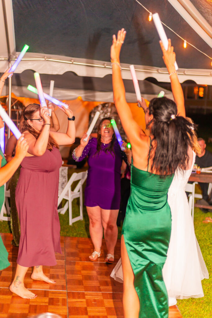 Guests dancing with glow sticks at a wedding.