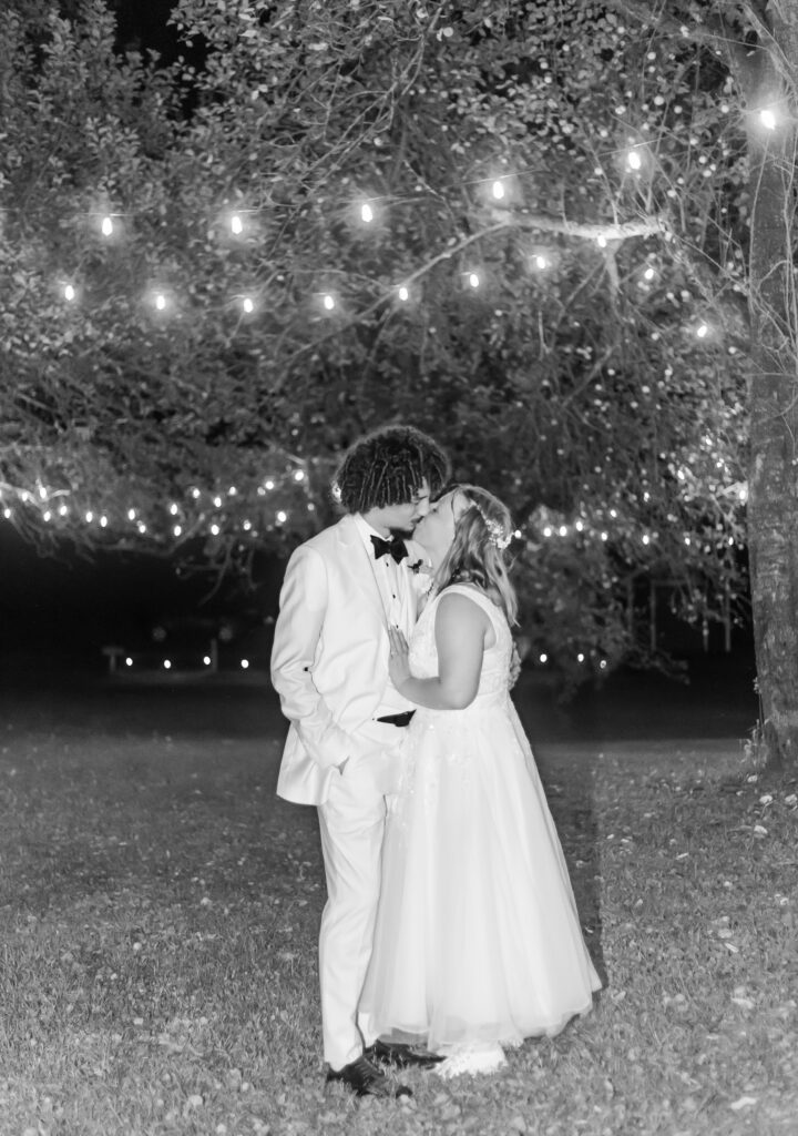 Bride and groom kiss under the twinkle lights 