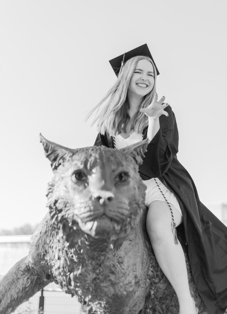 A college grad on the UNH Wildcat Statue in Durham, NH.