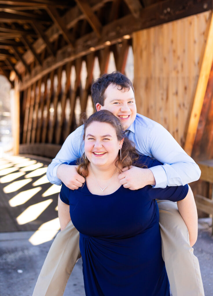 Gretchen gives Andrew a piggy back ride during their engagement session in NH.