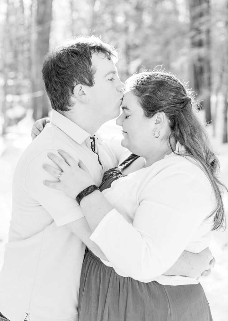 Andrew kisses Gretchen on the forehead at their winter engagement session on Squam Lake. 