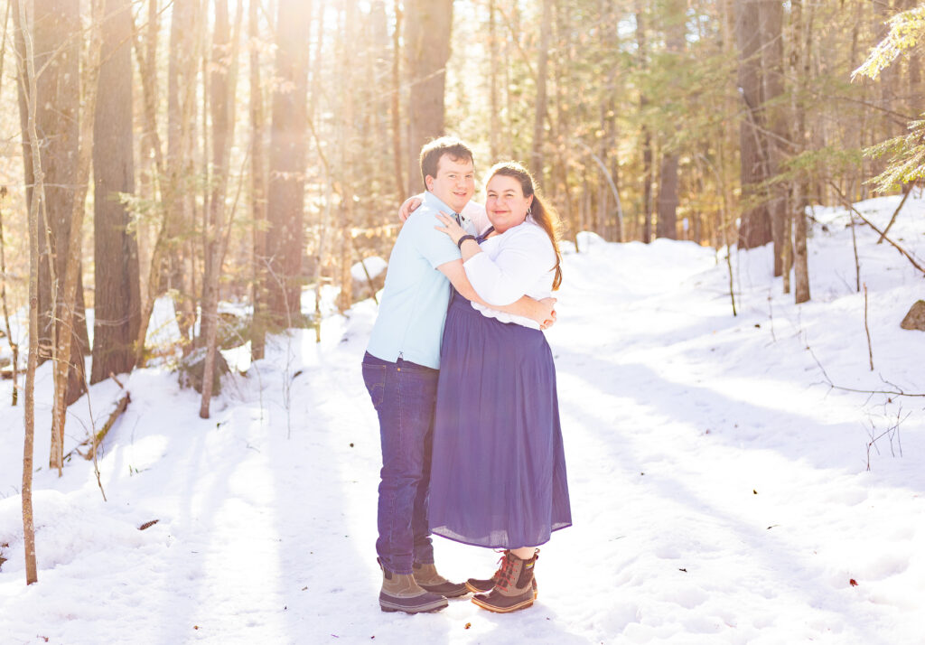 A couple holds each other in the golden hour light at their Lakes Region NH engagement session in Holderness NH.
