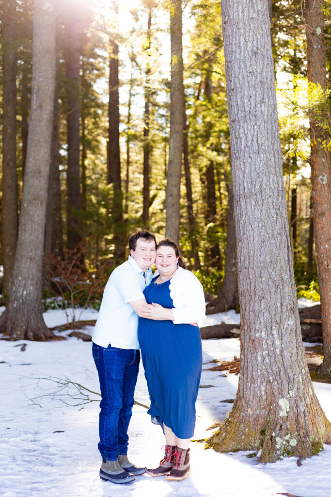 A couple holds each other at their wintry engagement session in New Hampshire.