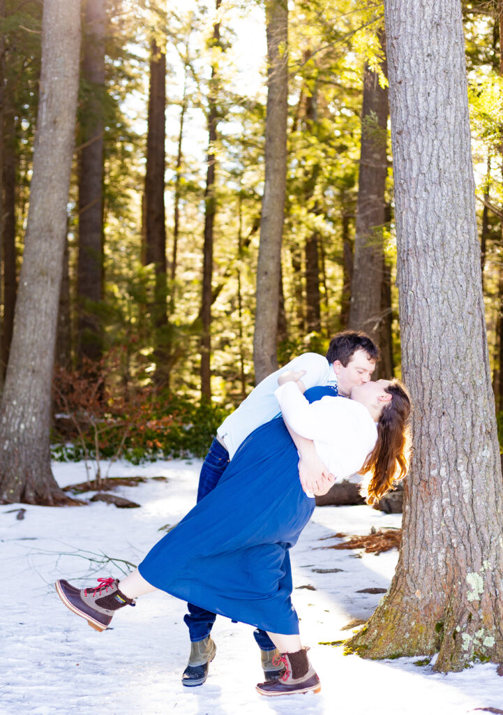 Andrew dips his fiance in the morning glow on Squam Lake at their engagement session in Holderness NH.