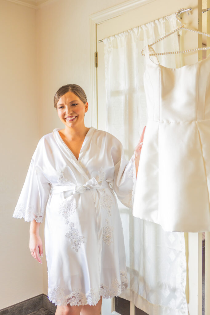 Bride standing next to her wedding dress.