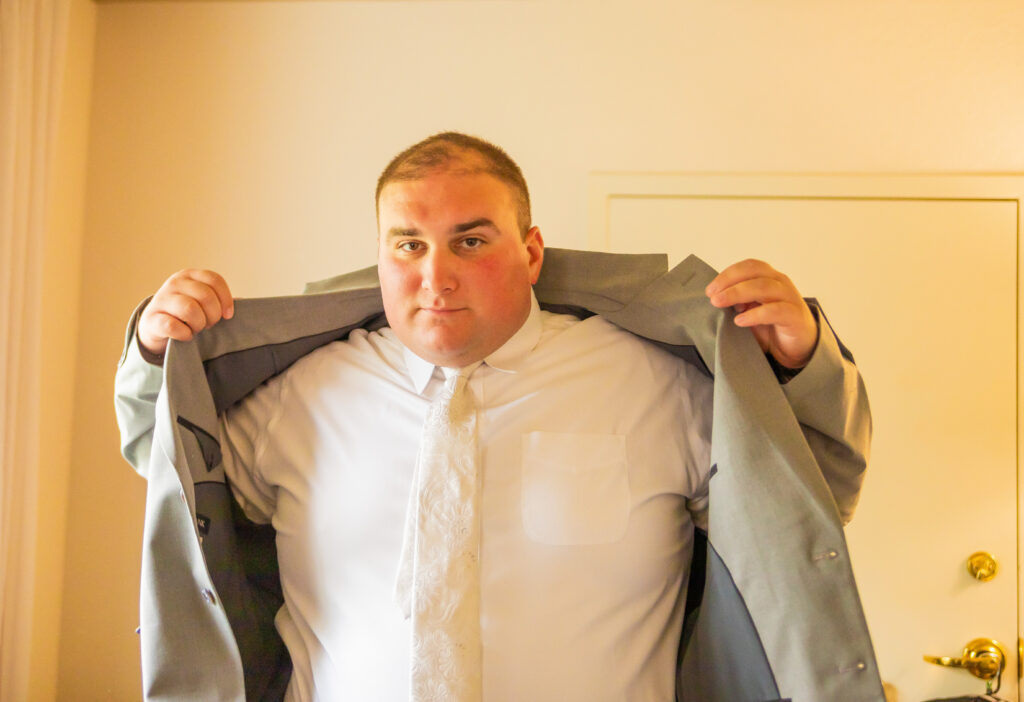 Groom putting his suit jacket on for his wedding day.