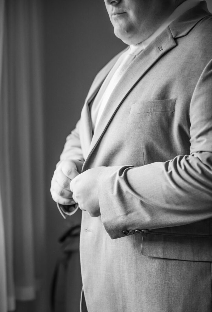 Groom buttons his jacket.