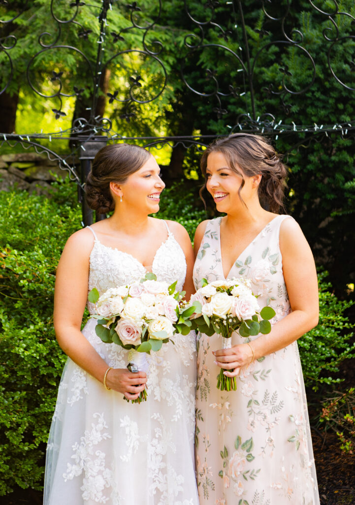 Bride and maid of honor smile and laugh together.