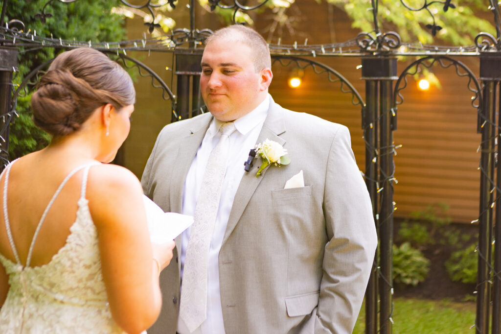 Groom admires his bride while she reads her vows to him.