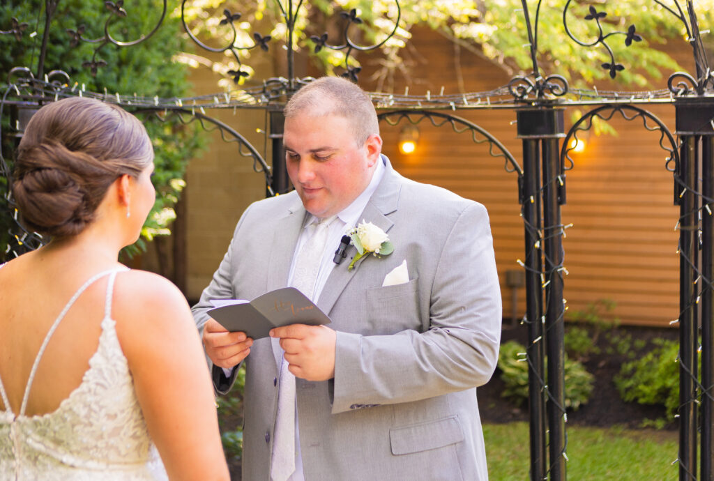 Groom reading vows in a NH garden venue.