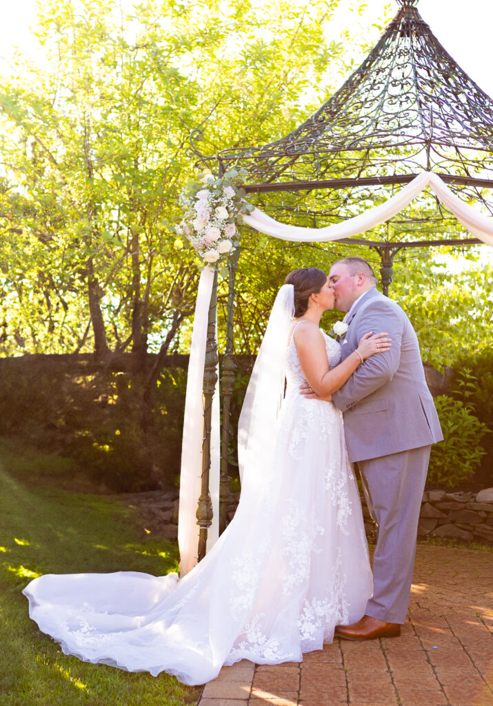 Bride and groom share their first kiss as a married couple at their Wedding by Wedgewood.