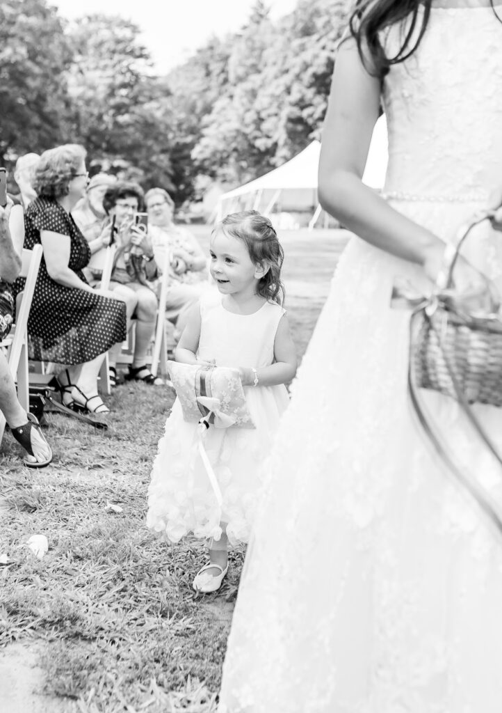 Little flower girl smiles while walking down the aisle.