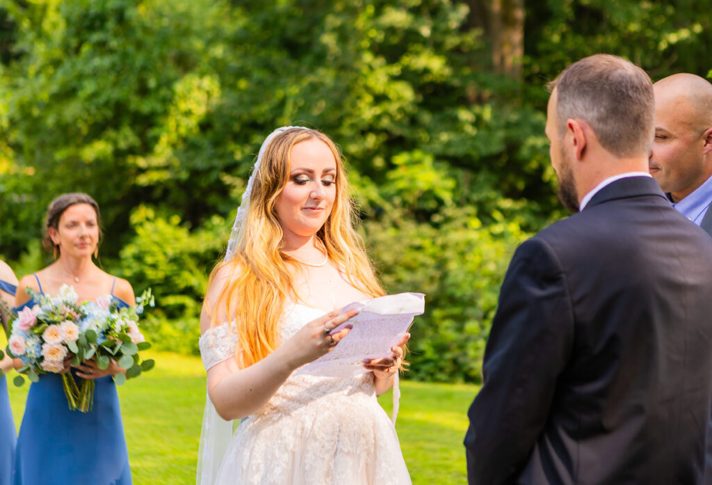 The bride reads her vows to her future husband at their field wedding in NH.