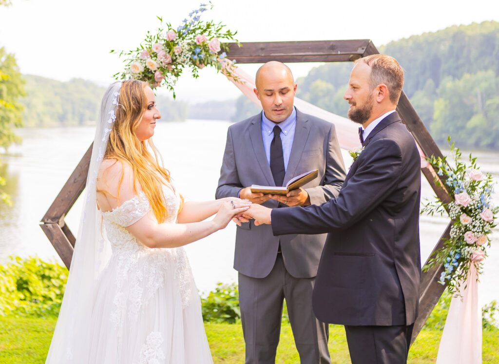 Bride putting a wedding ring on her groom at their summer wedding in NH.