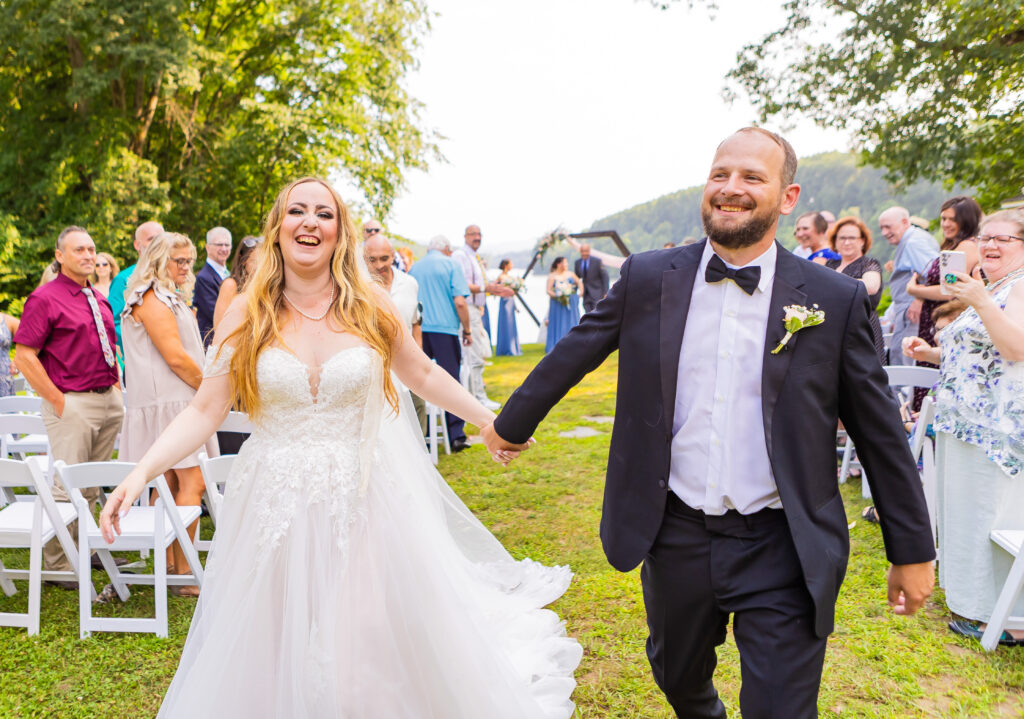 Bride and groom laugh together walking down the aisle.