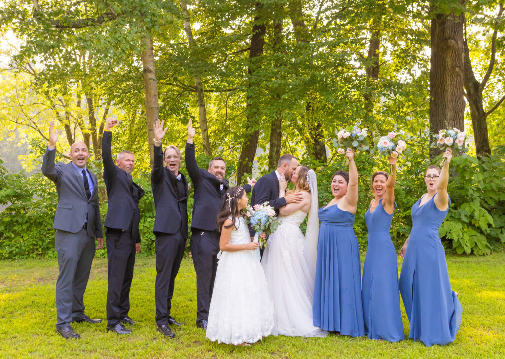 Wedding party cheers for the bride and groom while they share a kiss.