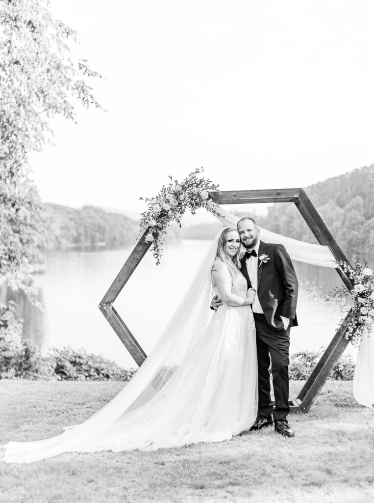 Bride and groom in front of their arbor at their wedding venue overlooking the Connecticut River in Westmoreland, NH.