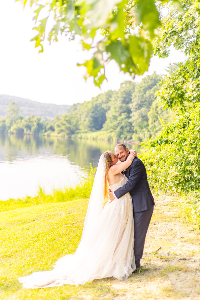 Bride kissing her groom under a willow tree.