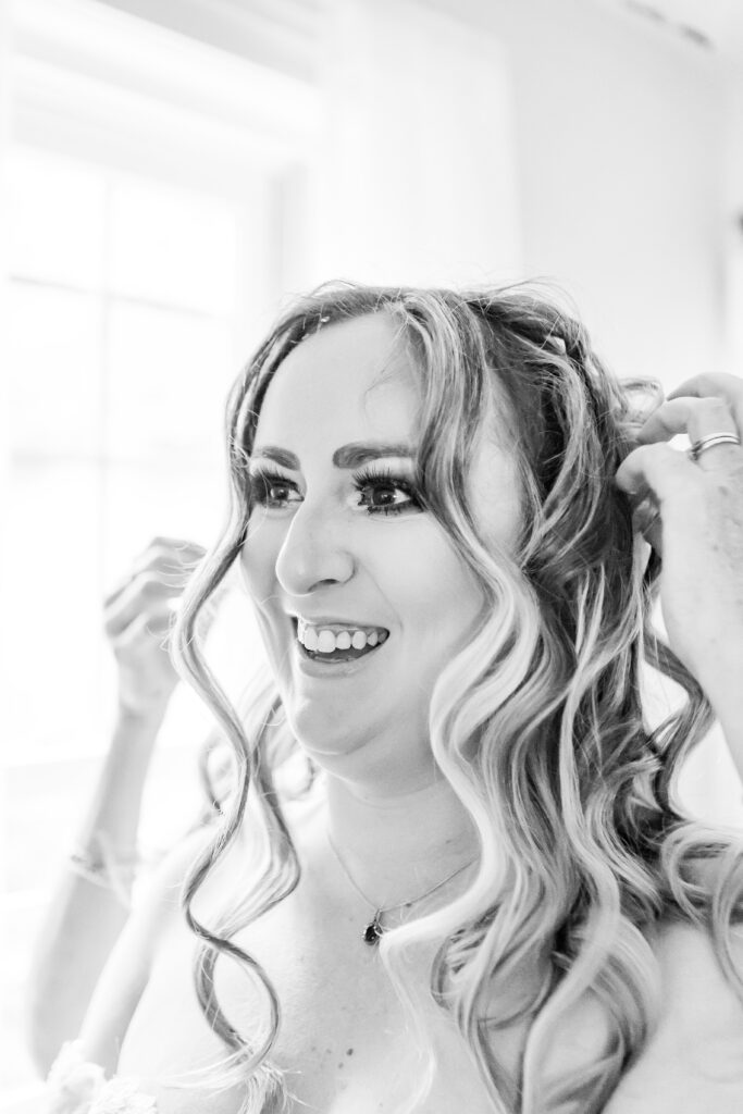 Bride smiling while having her hair done on her wedding day at Stone Garden.