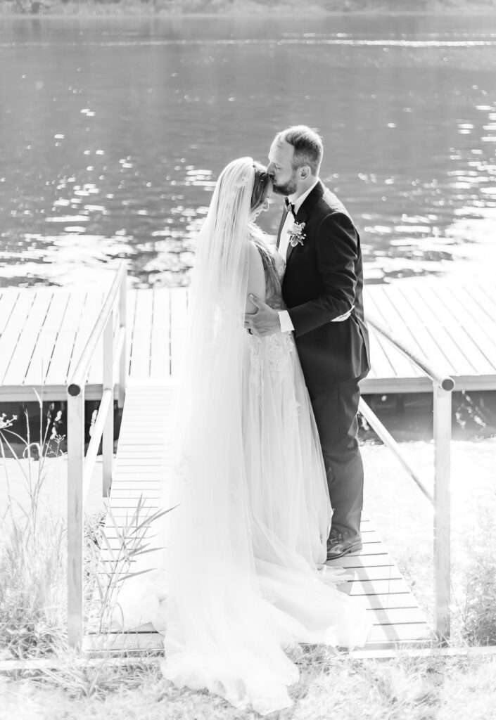 Groom kisses his bride on the forehead in front of the river in Westmoreland, NH.