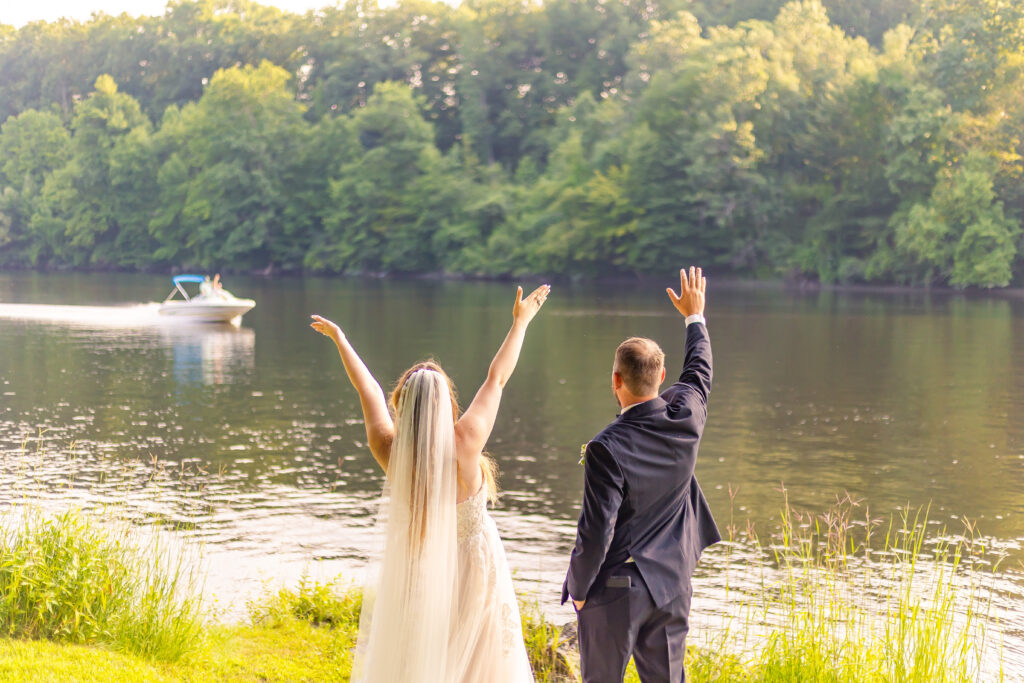 Bride and groom cheer for the boat going by.