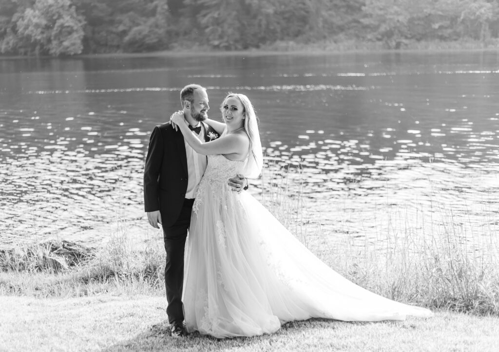 Bride and groom standing together in front of the Connecticut river in Keene, NH.