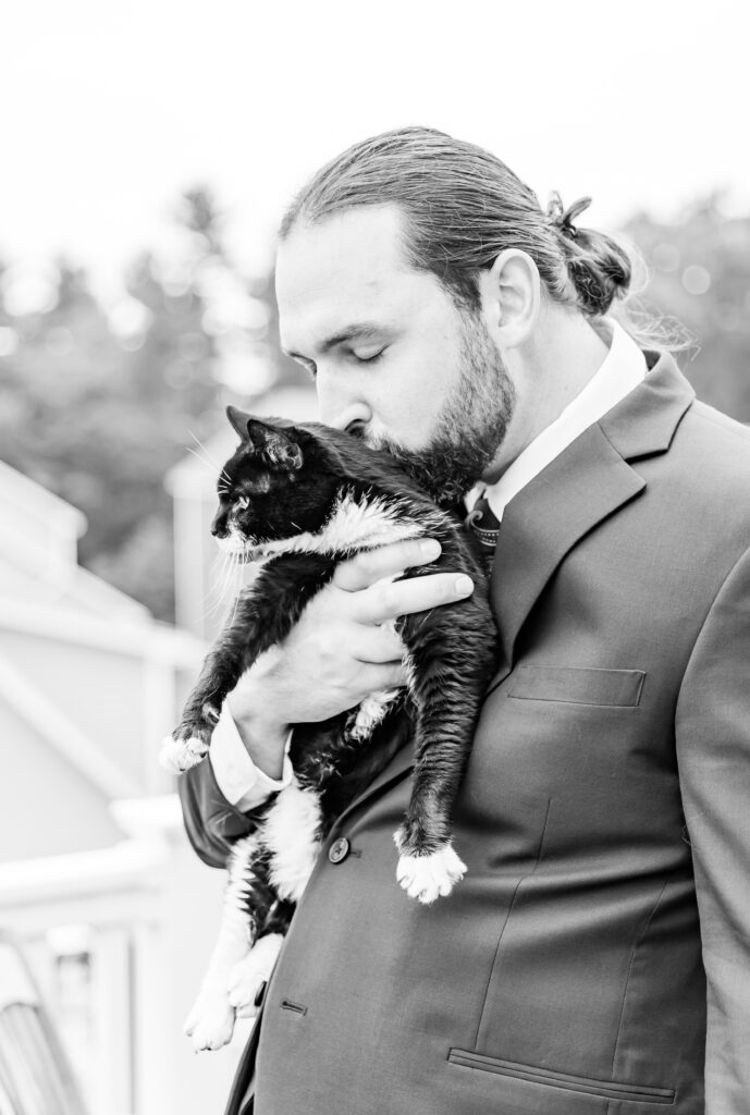 Groom kisses his kitty on the head.