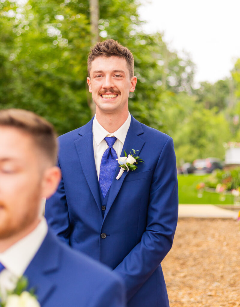 Groomsmen smiles as he is walking down the aisle.