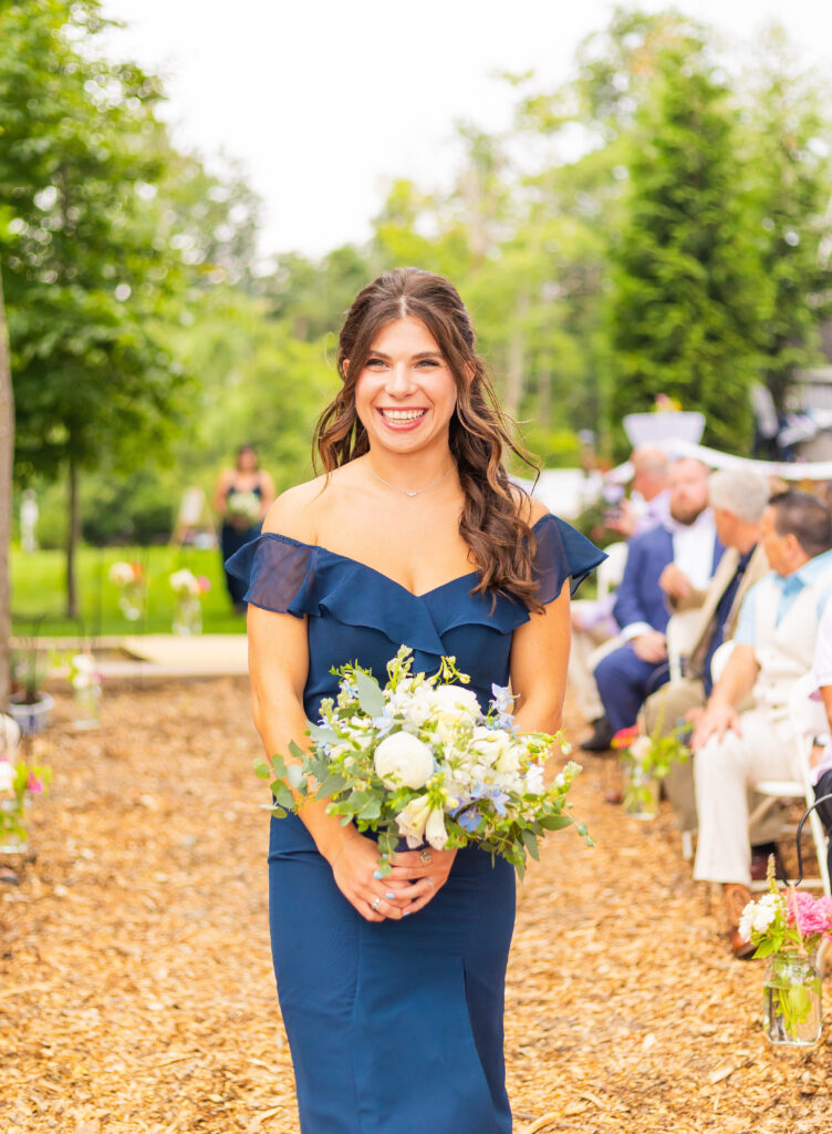 Bridesmaid smiles as she walks up the wedding ceremony aisle.