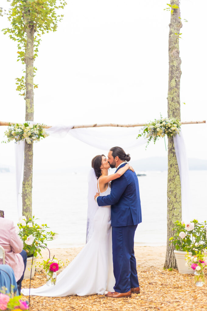 Bride and groom share their first kiss at their Lake Winnipesaukee wedding.