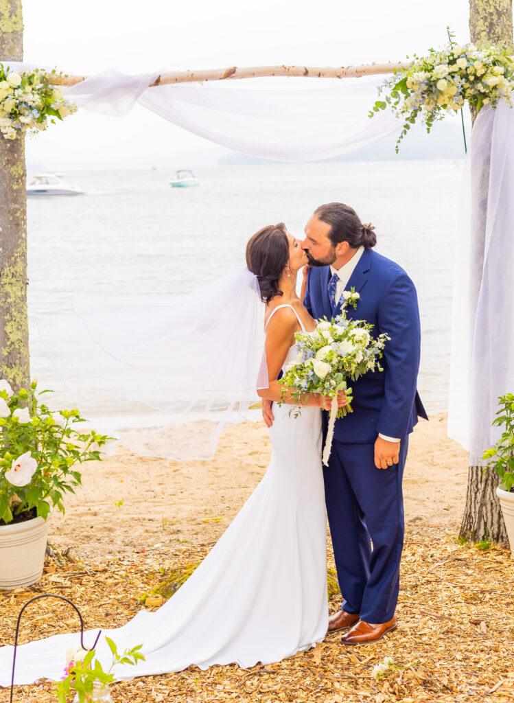 Bride and groom sharing a kiss in front of the NH lakefront wedding venue.