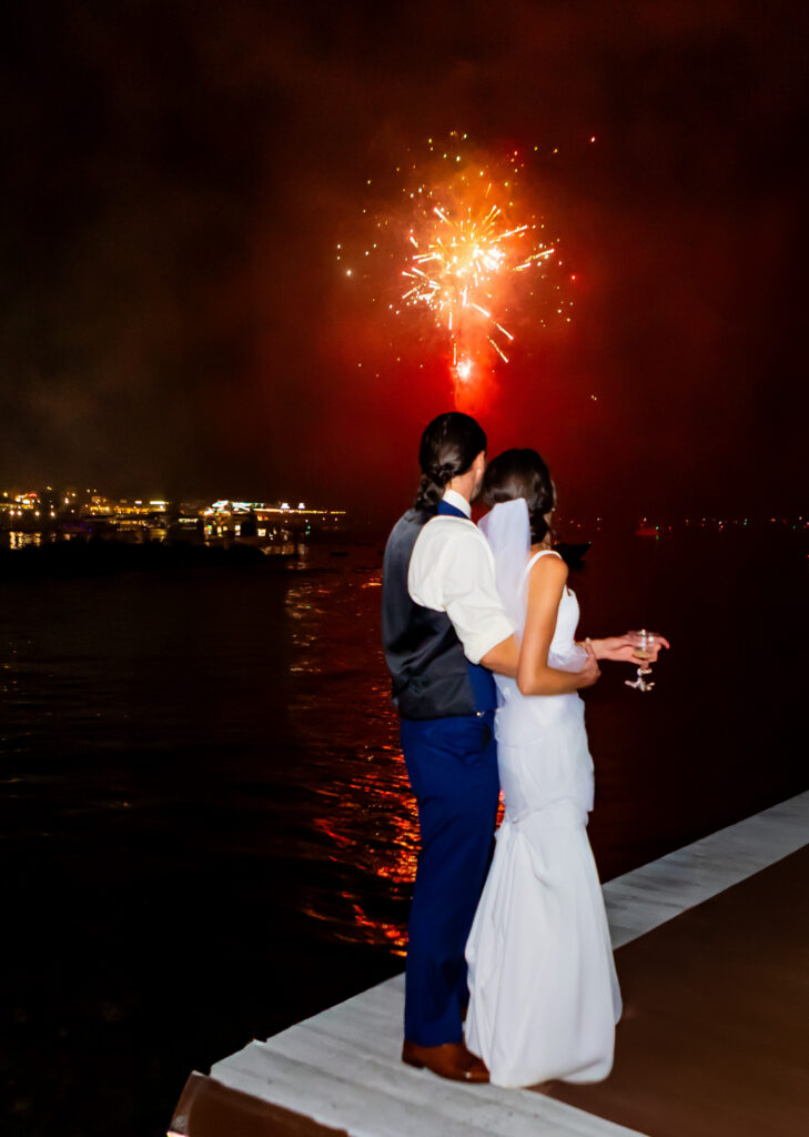 Bride and groom hold eachother and watch the fireworks.