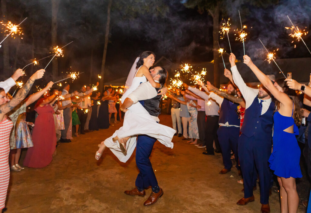 Groom carries his bride during their sparkler exit.