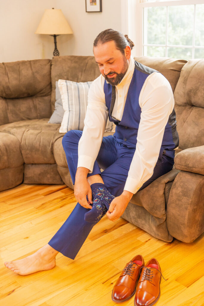 The groom is putting his shoes on for his wedding in Meredith, NH.