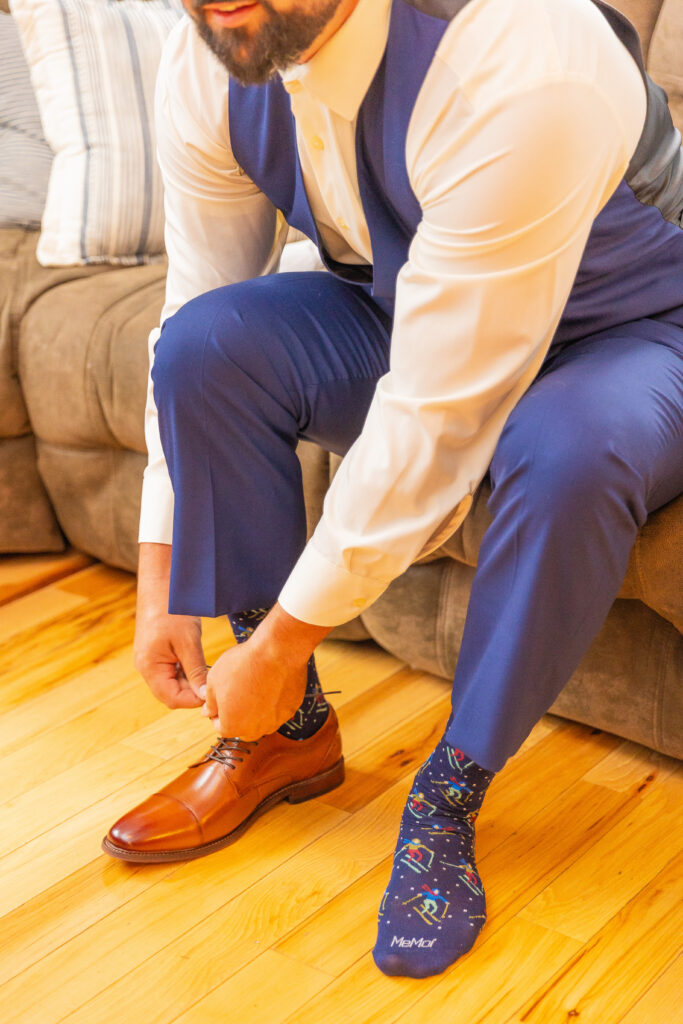 Groom is putting his shoes on for his Lake Winnipesaukee wedding.